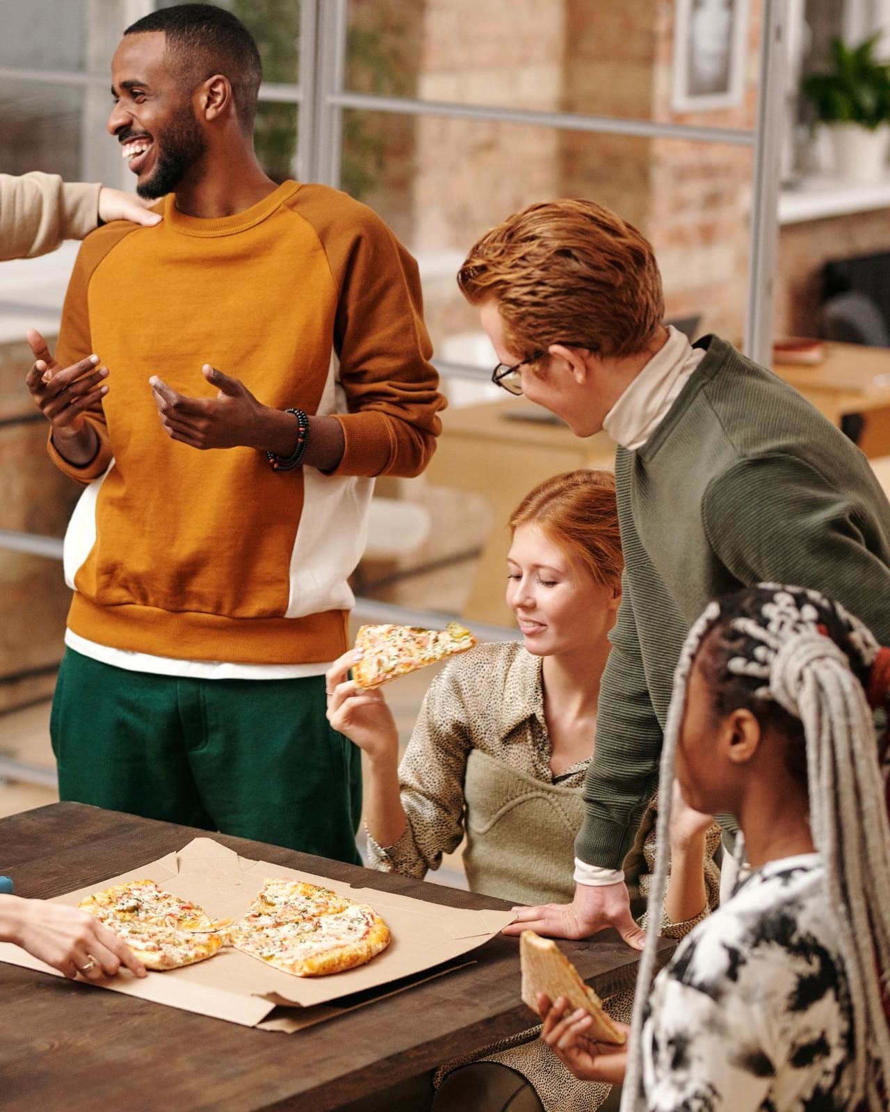 A mixed group laughing together over pizza